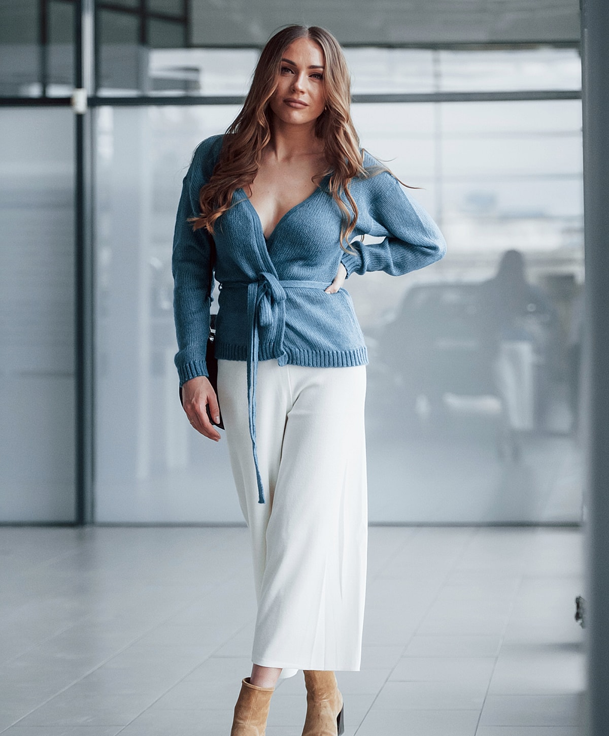 Woman in stylish blue cardigan and white pants.